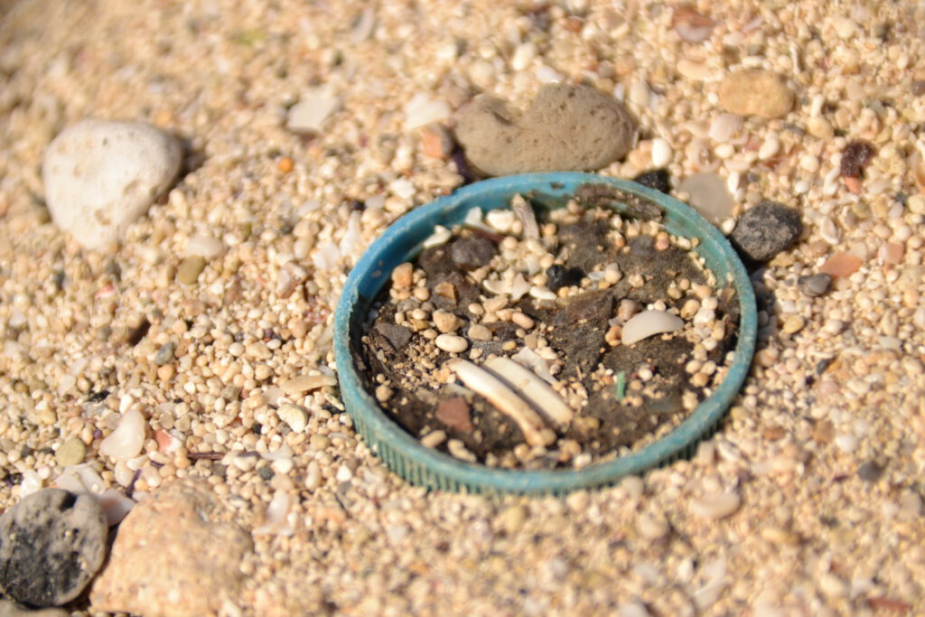 blauer plastikdeckel am strand